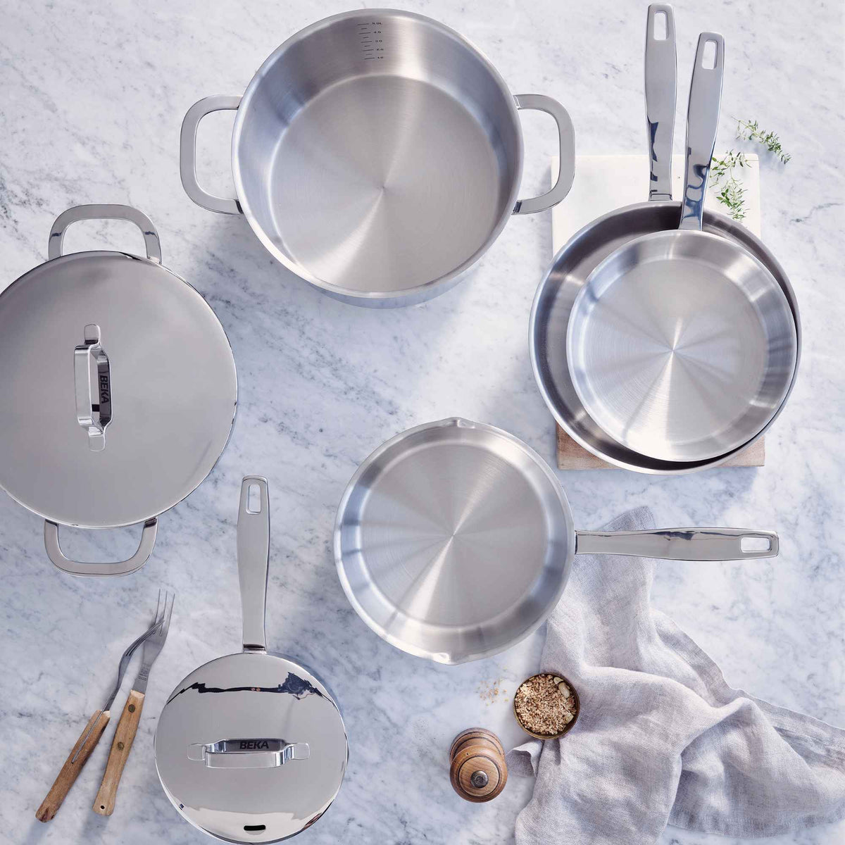 Stainless steel cookware arranged on a marble kitchen counter
