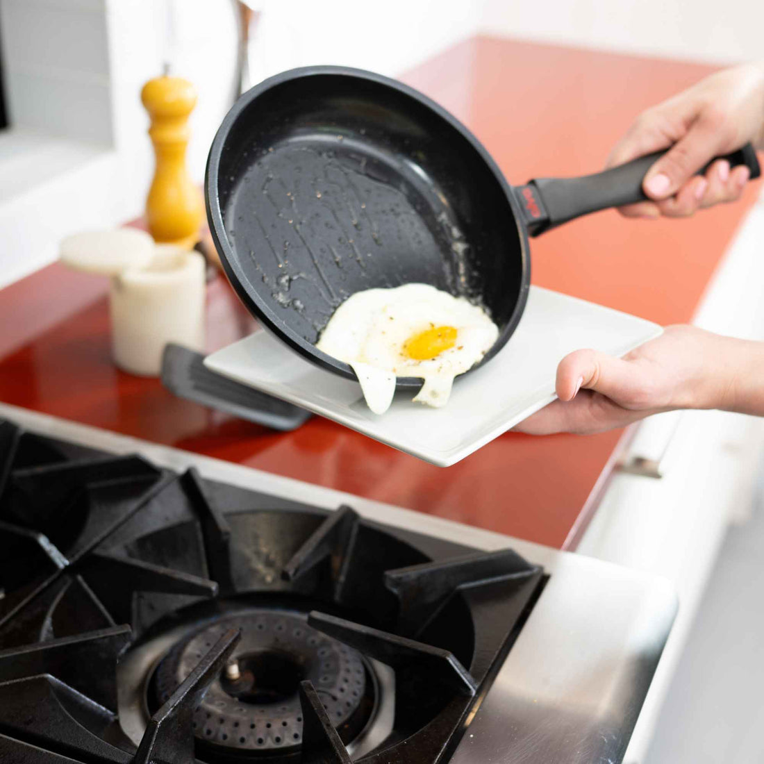 Sliding a fried egg out of an Alva Energy ceramic nonstick frying pan onto a plate over a gas stove