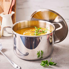 Alva Maestro 5-ply stainless steel stock pot of orange soup with parsley and the lid propped open on a counter