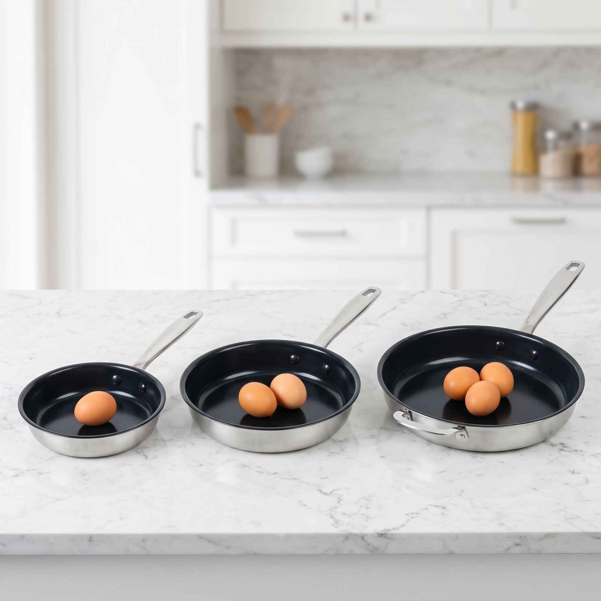 Alva Maestro frying pans in three sizes holding one, two and three eggs on a marble kitchen counter