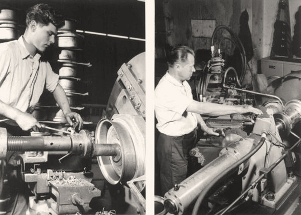 Two men operating industrial machinery in a workshop setting.