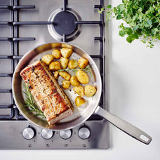 Overhead view of pork loin and roasted potatoes in an Alva Maestro 5-ply stainless steel frying pan on a gas cooktop