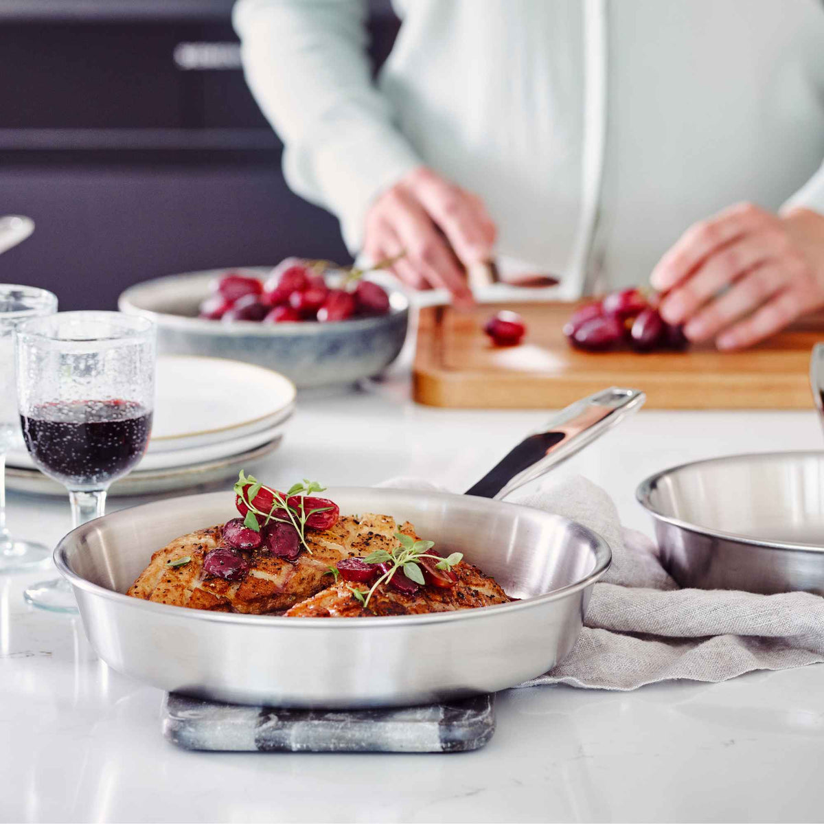 Alva Maestro 5-ply stainless steel frying pan serving roast chicken with grapes on a set dinner table