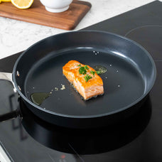 Salmon fillet searing in an Alva Maestro ceramic nonstick frying pan on an induction cooktop