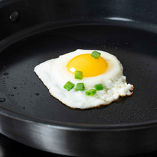 Close-up of a fried egg topped with scallions in an Alva Maestro 5-ply ceramic nonstick frying pan