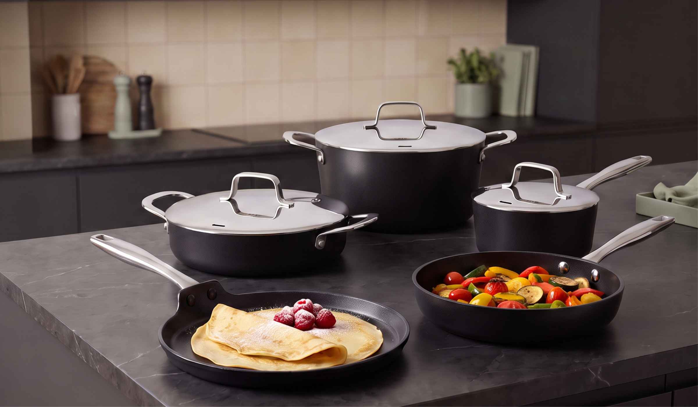 Alva black ceramic cookware set in a warm kitchen with crepes and sautéed vegetables