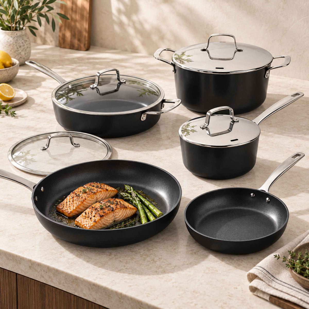 Alva Maestro ceramic nonstick cookware set on a marble counter with salmon and asparagus in the frying pan
