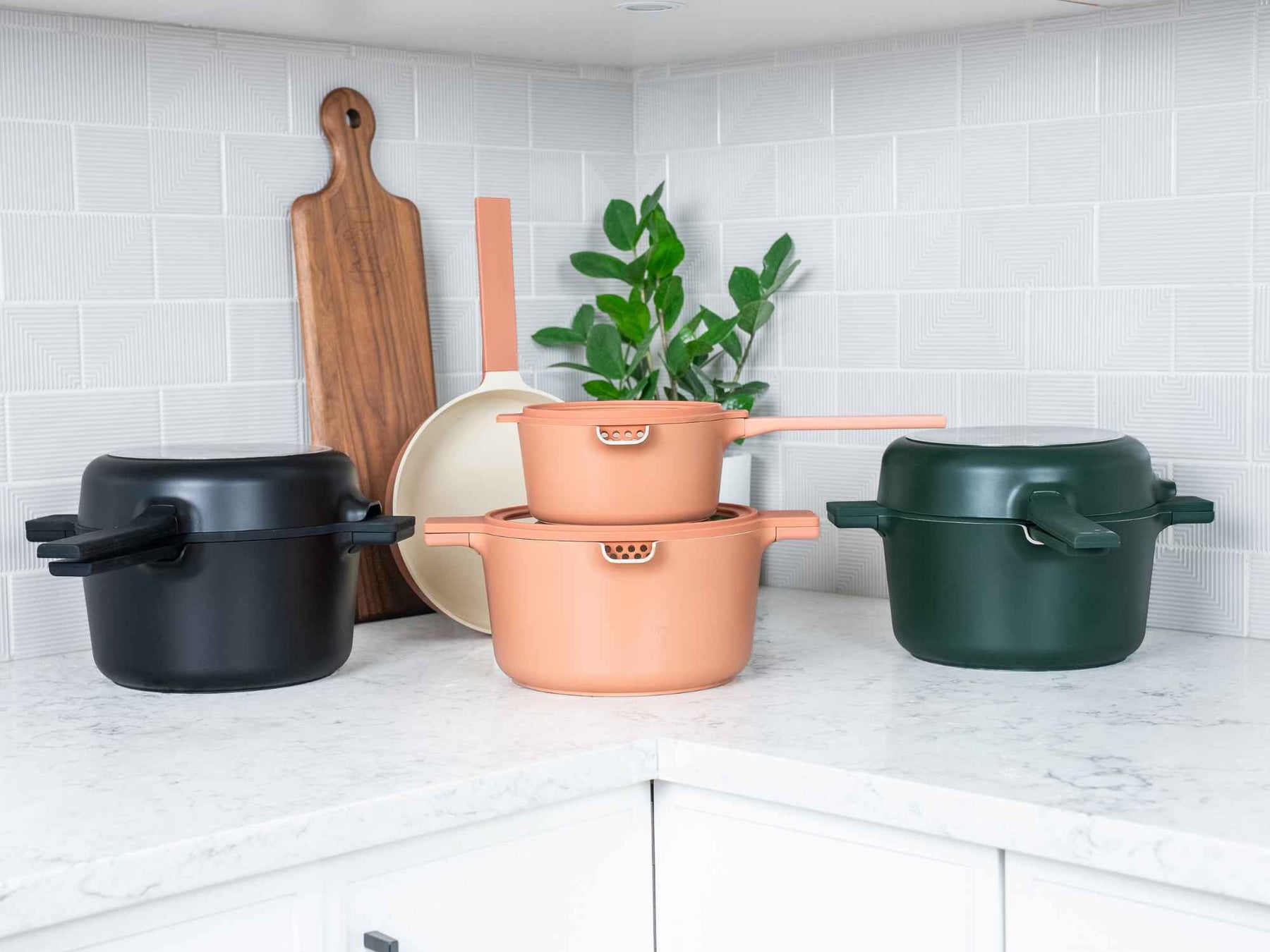 Alva Neat cookware in black, peach and green on a marble kitchen counter