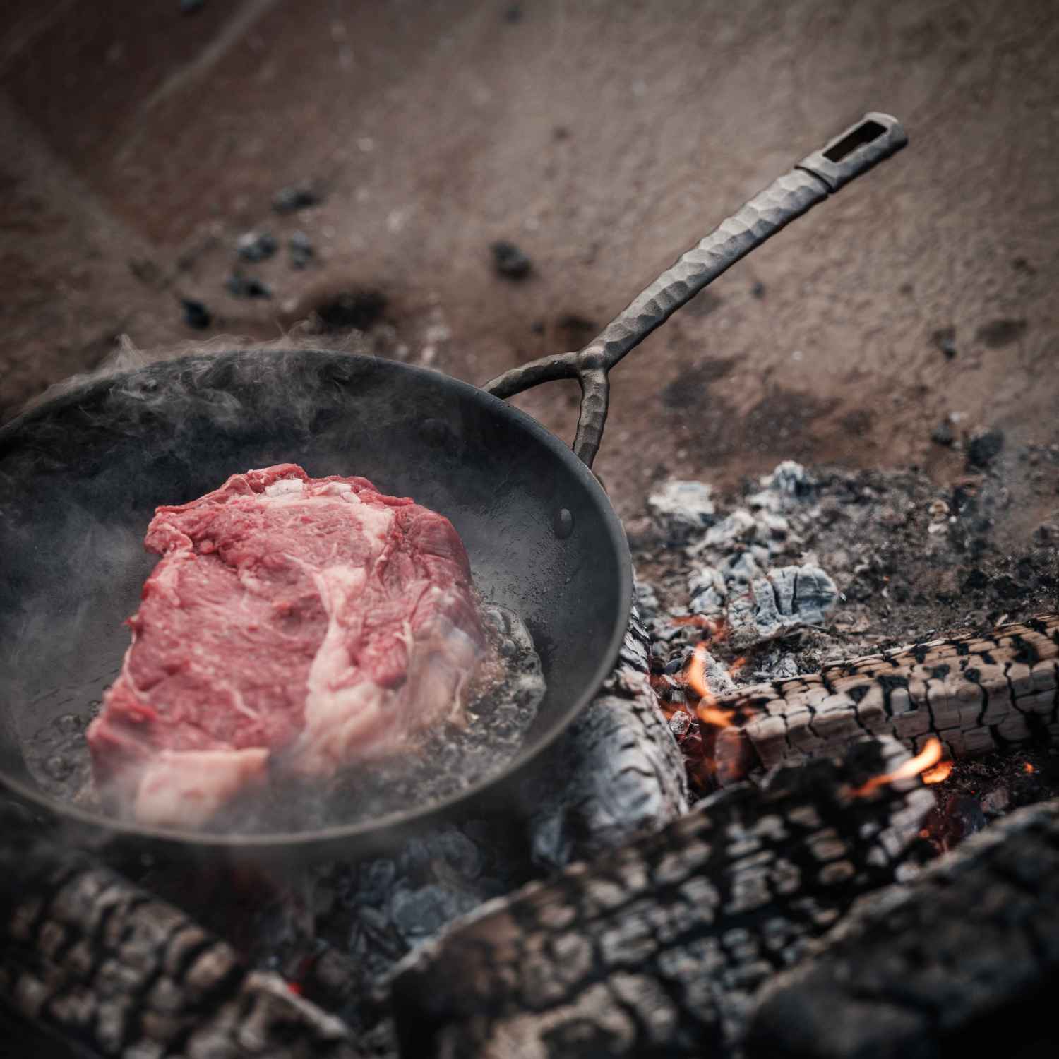 Alva Artist carbon steel frying pan cooking steak over an open fire