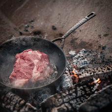 Alva Artist carbon steel frying pan cooking steak over an open fire